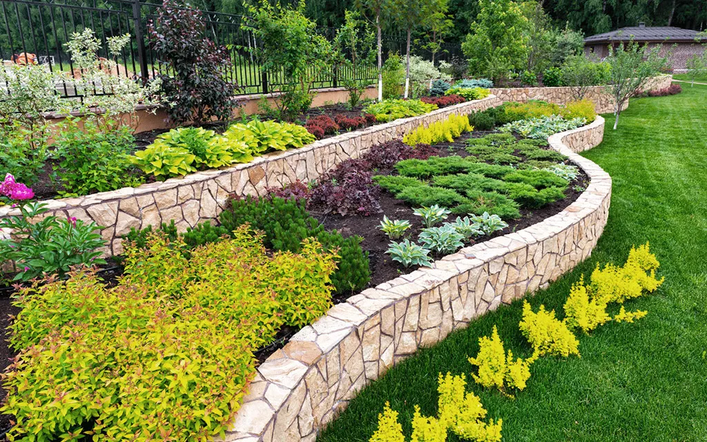 Jardin en terrasses aux murs sinueux et plantations abondantes